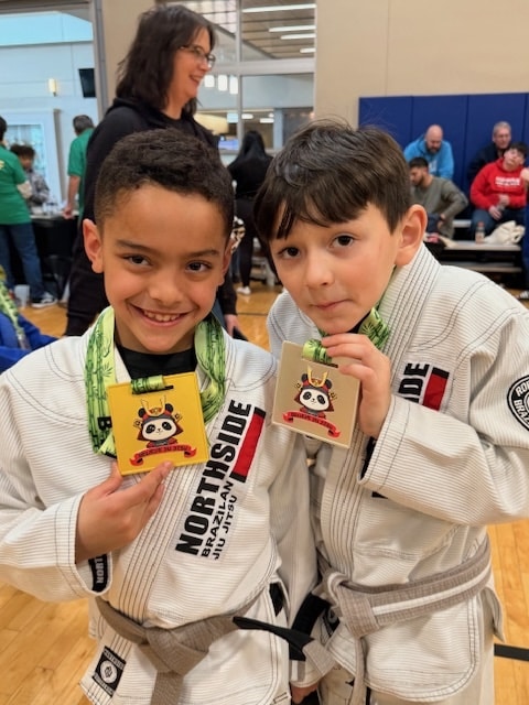 North Side Brazilian Jiu Jitsu students smiling holding medal from competition.