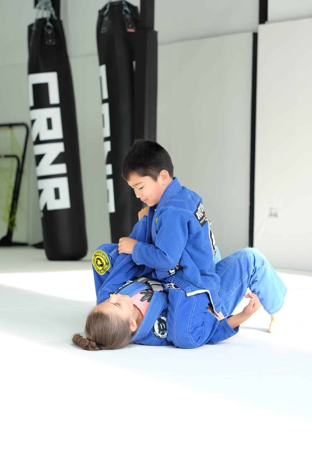 North Side Brazilian Jiu Jitsu young students grappling on mat wearing gi uniforms.